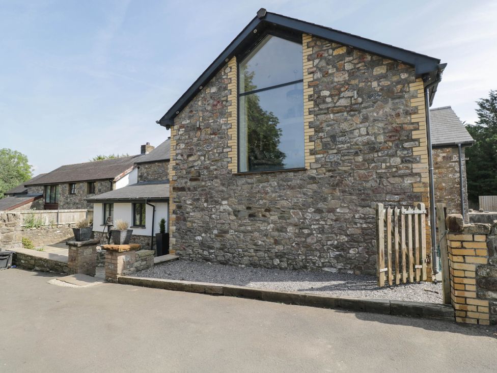 A house with stone walls and a gravel area at Llanfarach Farmhouse near Pontyclun