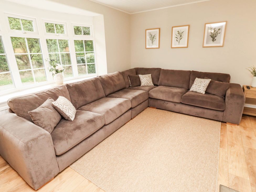 A living room with a sofa and windows at Hedley Dene Cottage in Longhorsley