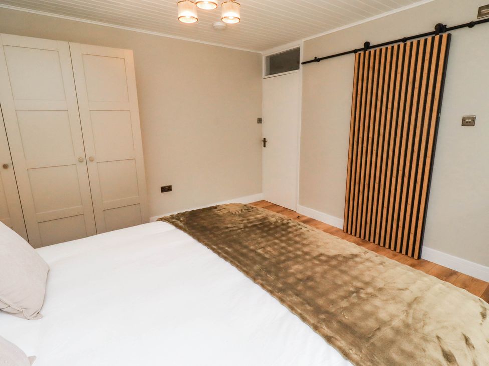A bedroom with a bed and wardrobe at Hedley Dene Cottage in Longhorsley