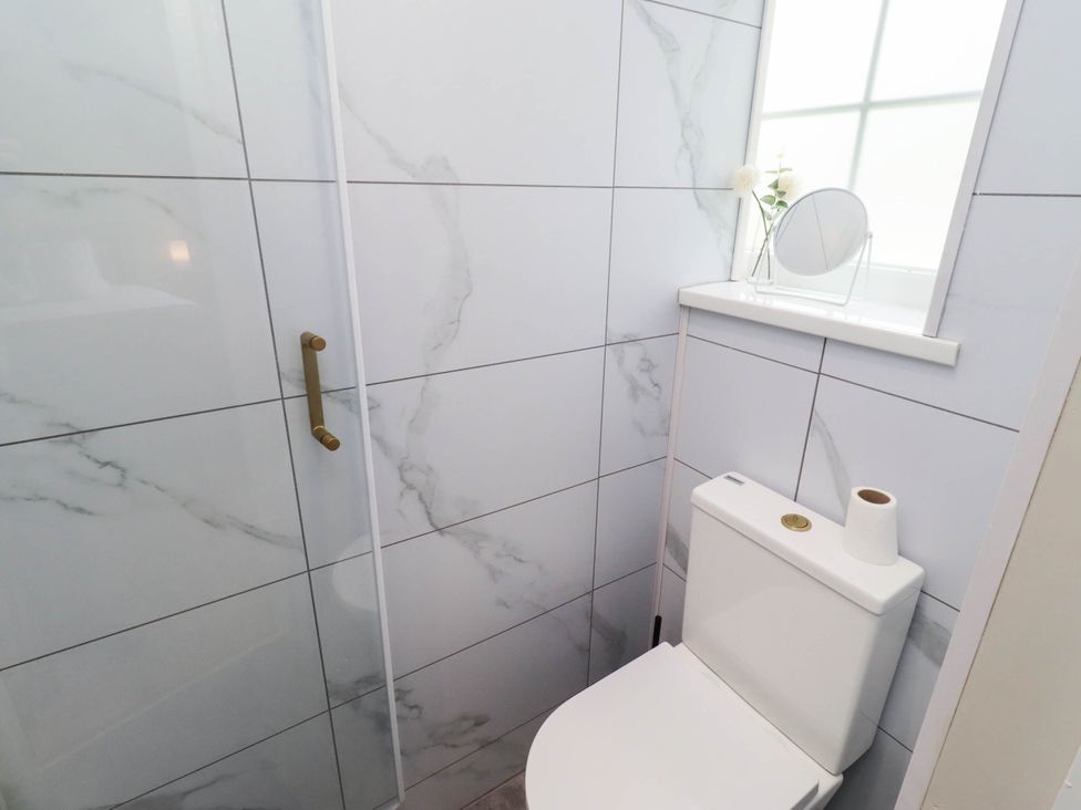 A bathroom with a toilet and shower at Hedley Dene Cottage Longhorsley