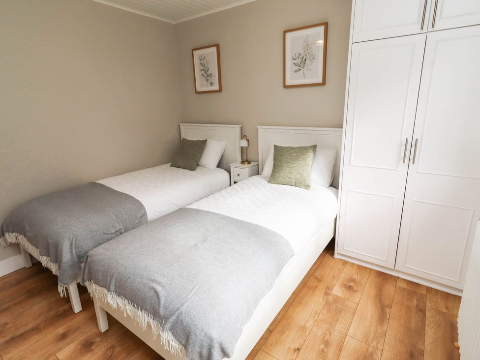 A bedroom with two beds and a wardrobe at Hedley Dene Cottage Longhorsley