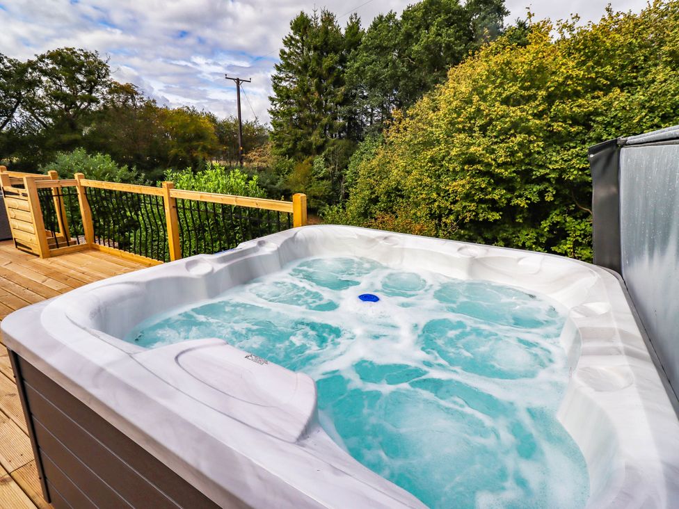 A hot tub on a wooden deck at Hedley Dene Cottage Longhorsley
