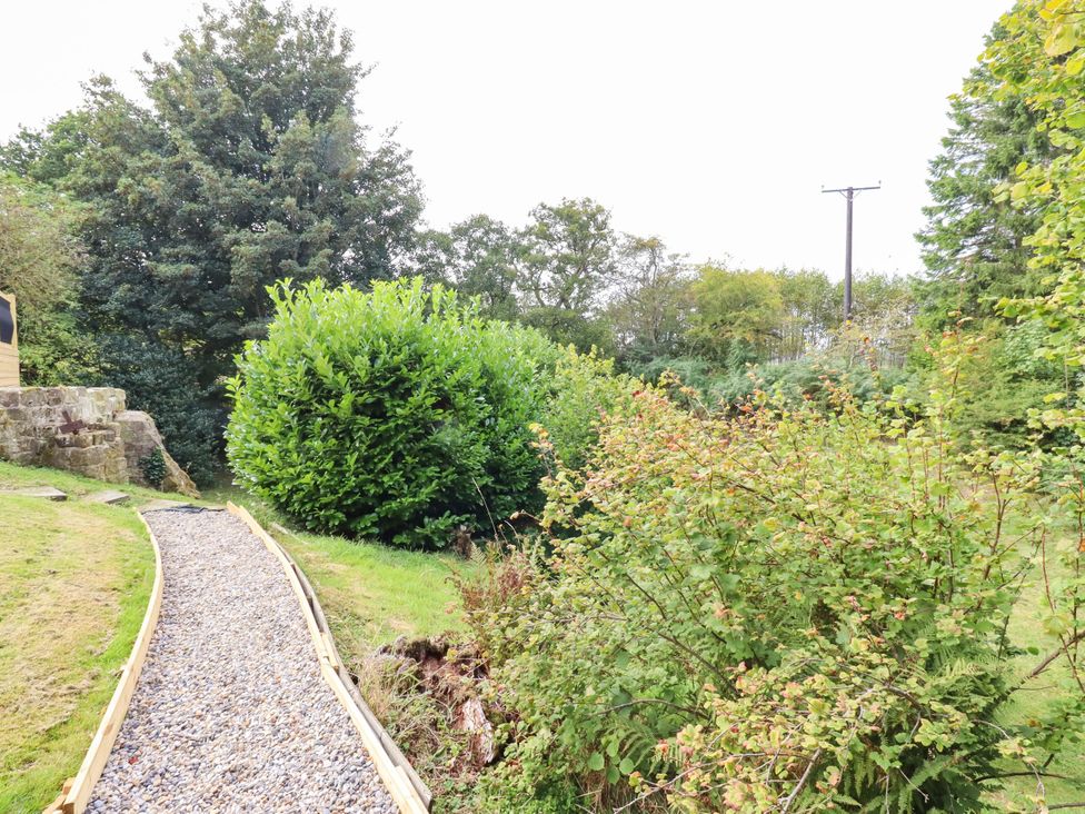 A garden with a gravel path and greenery at Hedley Dene Cottage in Longhorsley