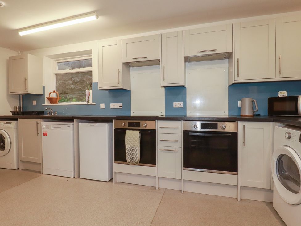 A kitchen with appliances including a washing machine and oven at Newseal House