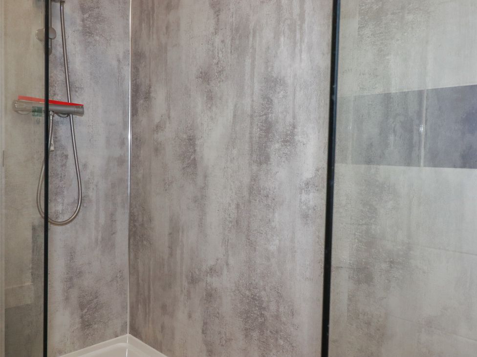 A shower area with a glass door and a showerhead at Newseal House