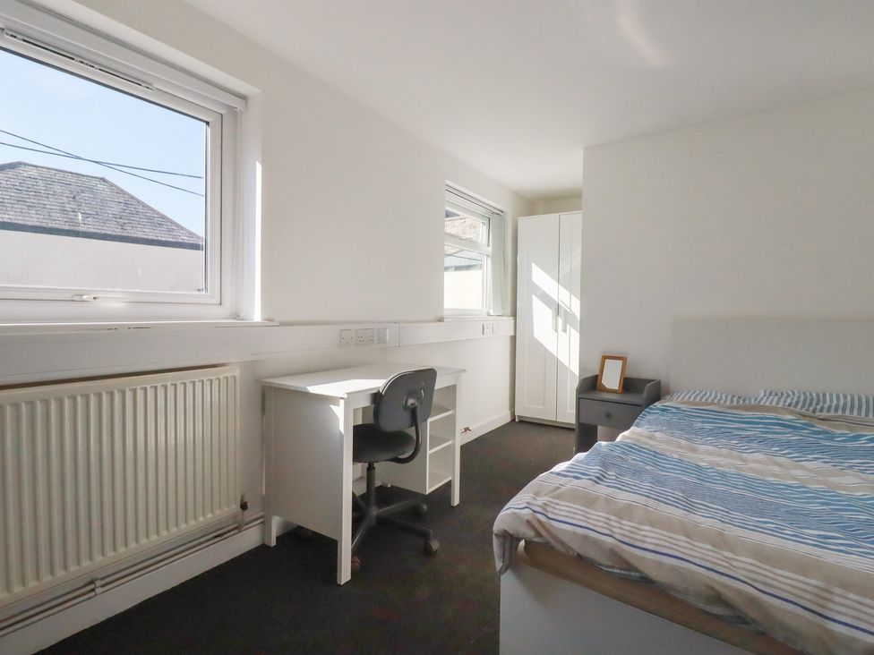 A bedroom with a bed, desk, and wardrobe at Newseal House