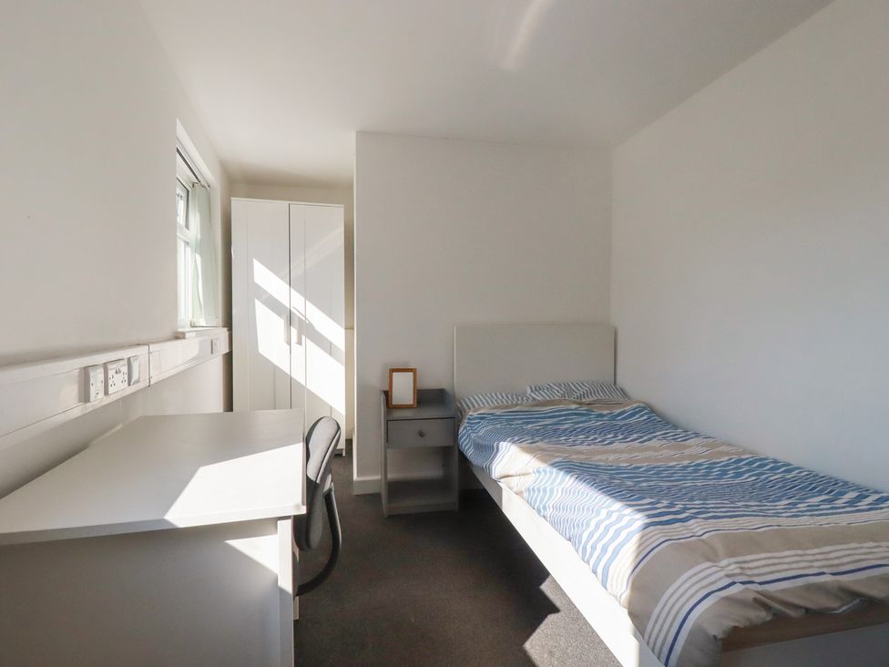 A bedroom with a bed, desk, and wardrobe at Newseal House