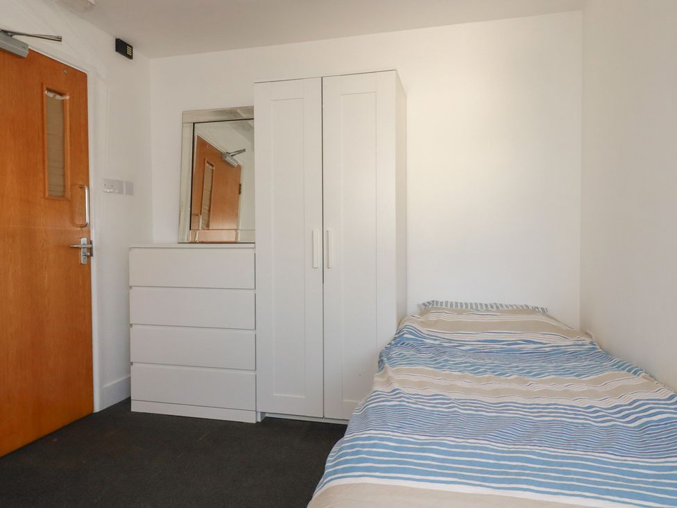 A bedroom with a bed, wardrobe, dresser, and mirror at Newseal House