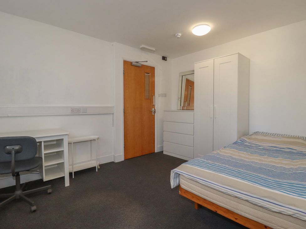 A bedroom with a bed, desk, chair, and wardrobe at Newseal House