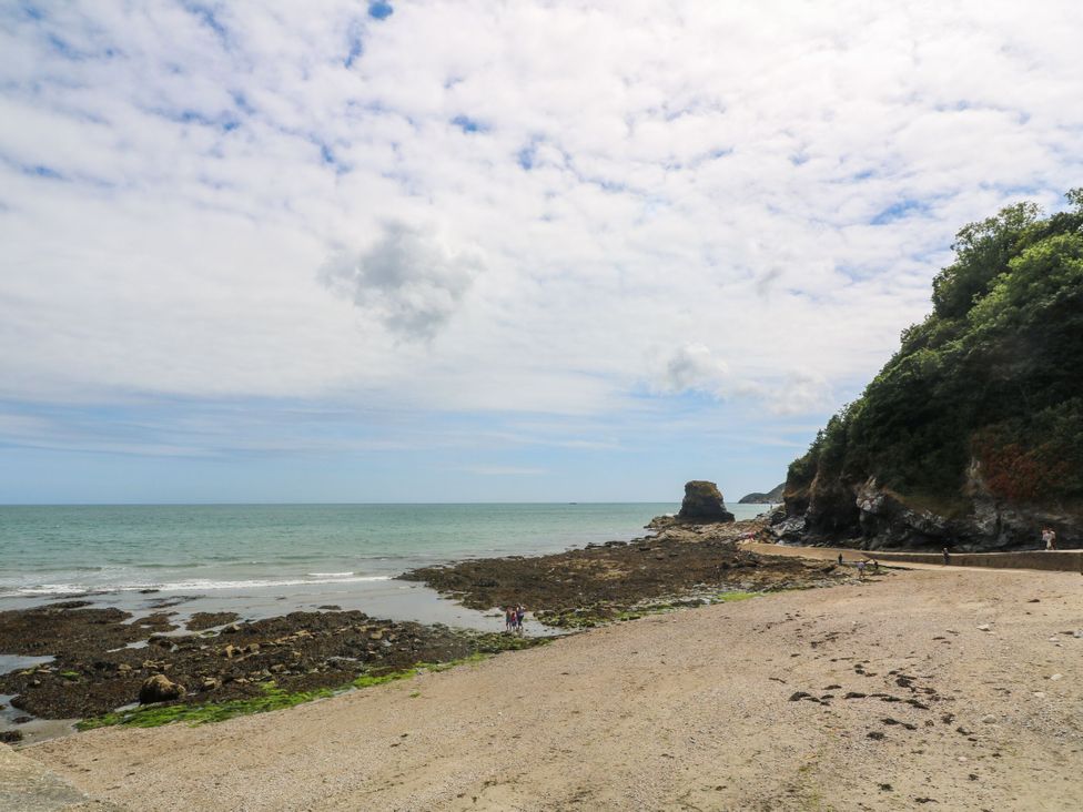 A beach with rocky shoreline and people at Newseal House St Austell