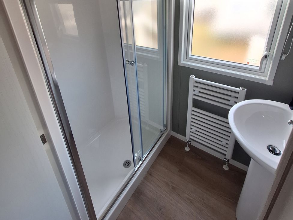 A bathroom with a shower, sink, and radiator at Haven Seashore, Ellerton Willerby Xtra, Great Yarmouth