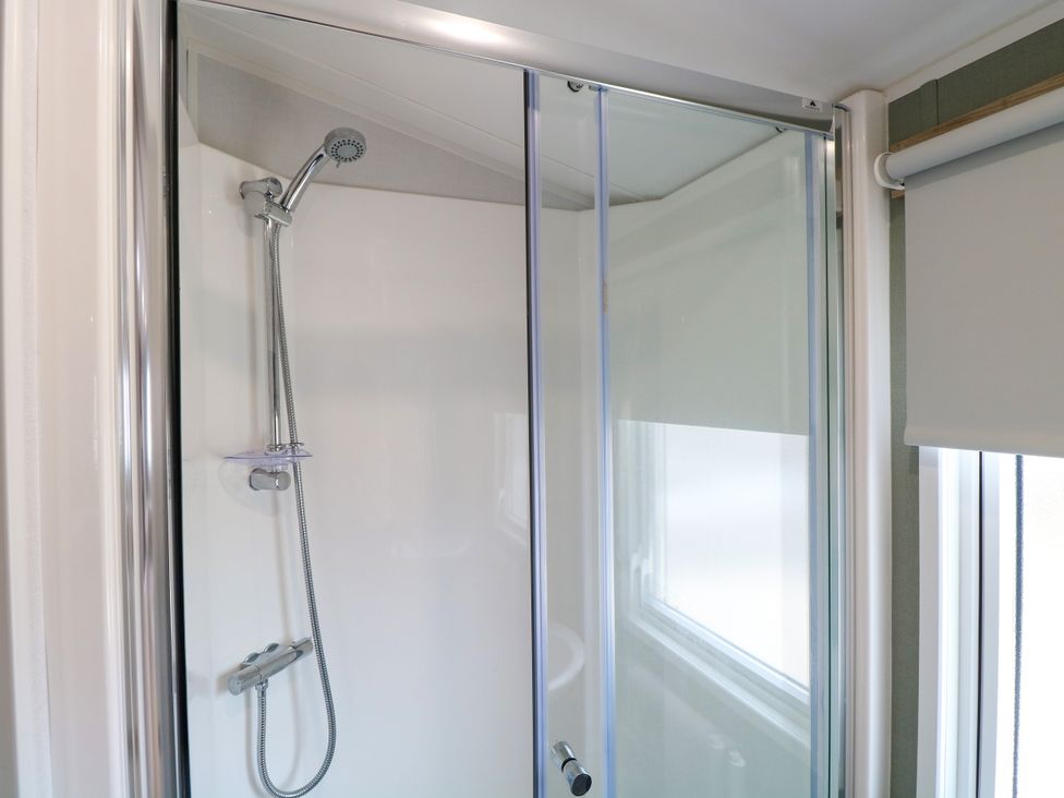 A shower with a glass door and faucet at Haven Seashore, Ellerton Willerby Xtra, Great Yarmouth