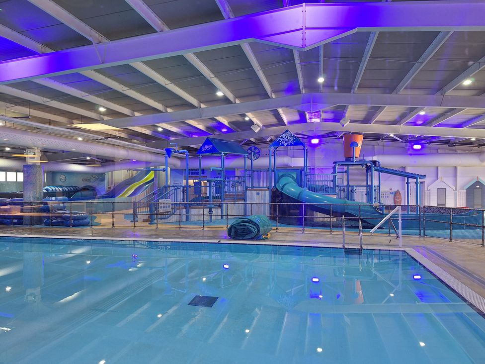 An indoor pool area with a water slide and play structure at Haven Seashore, Ellerton Willerby Xtra, Great Yarmouth
