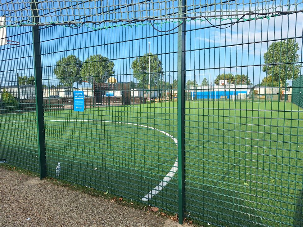 A sports field with a fence and artificial turf at Haven Seashore, Great Yarmouth