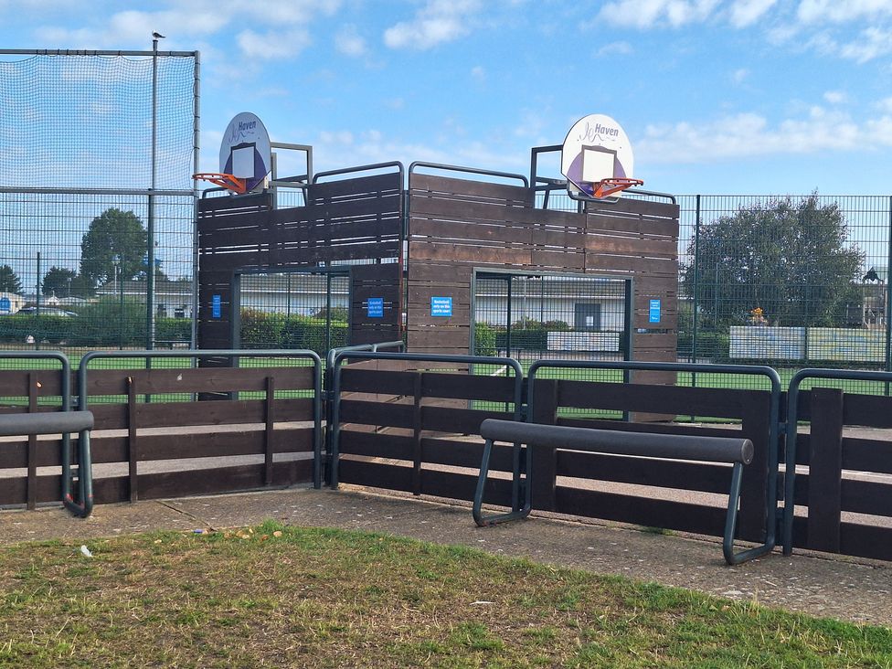 An outdoor basketball court with hoops and benches at Haven Seashore, Great Yarmouth