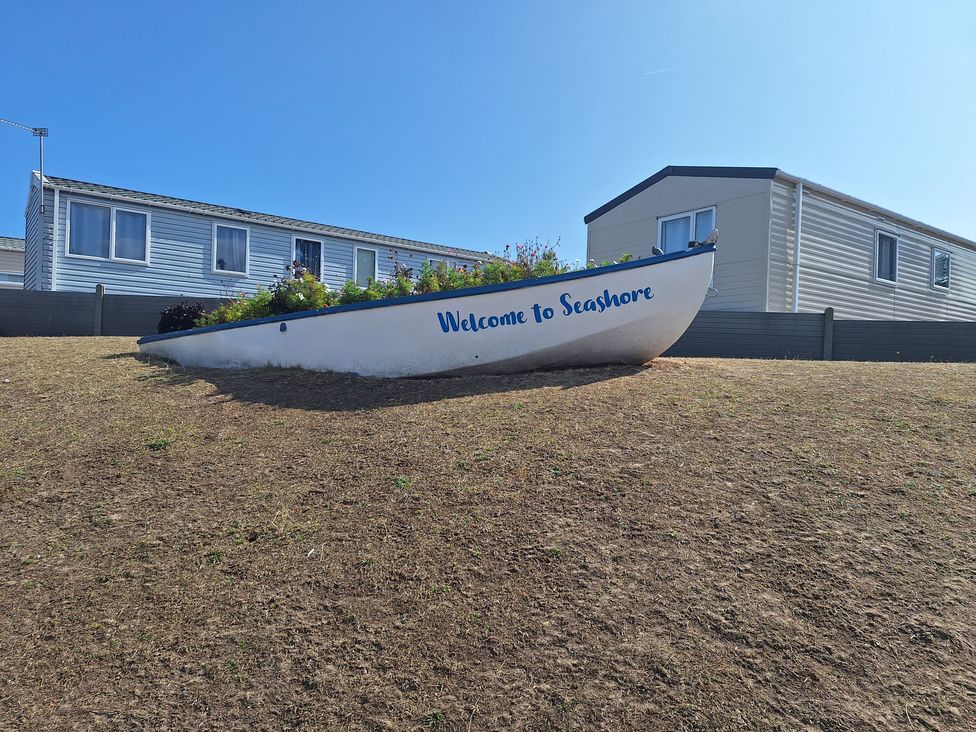 A boat in a garden with a house in the background at Haven Seashore, Great Yarmouth