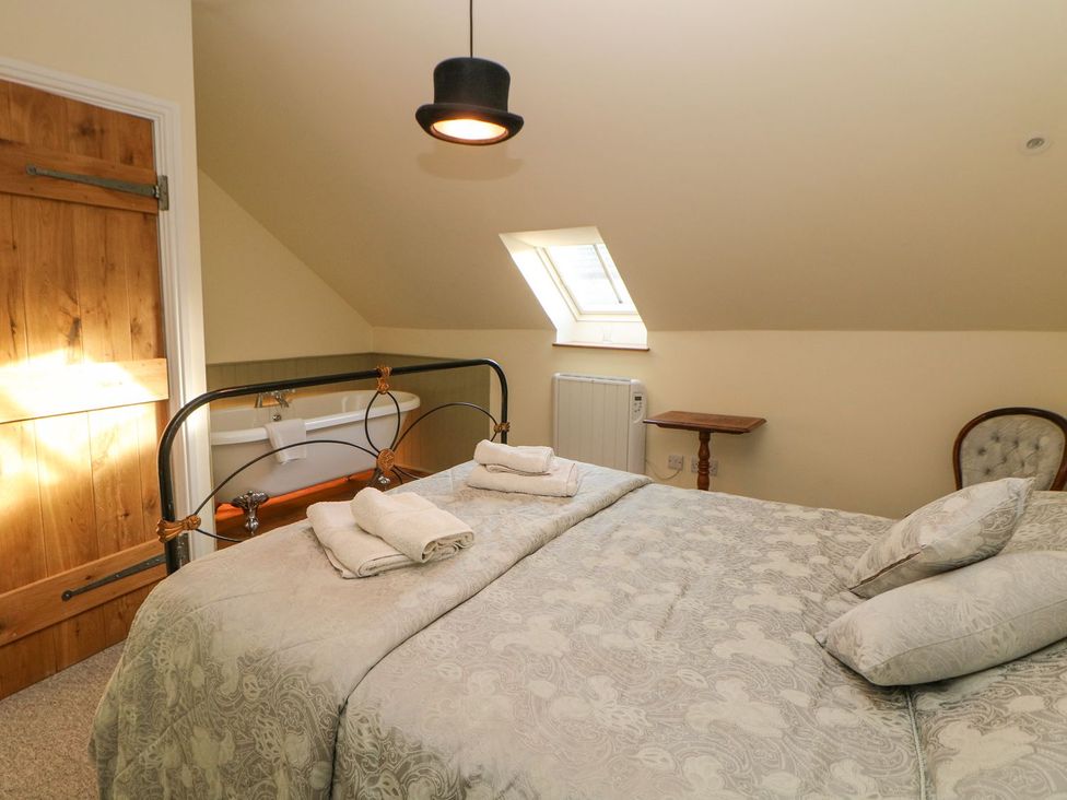 A bedroom with a bed and a bathtub at Laneside Barn in Calver