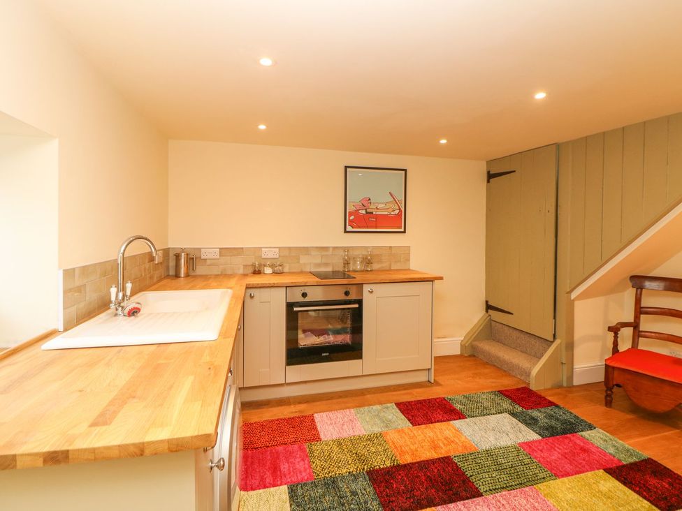 A kitchen with sink, oven, and staircase at Laneside Barn in Calver