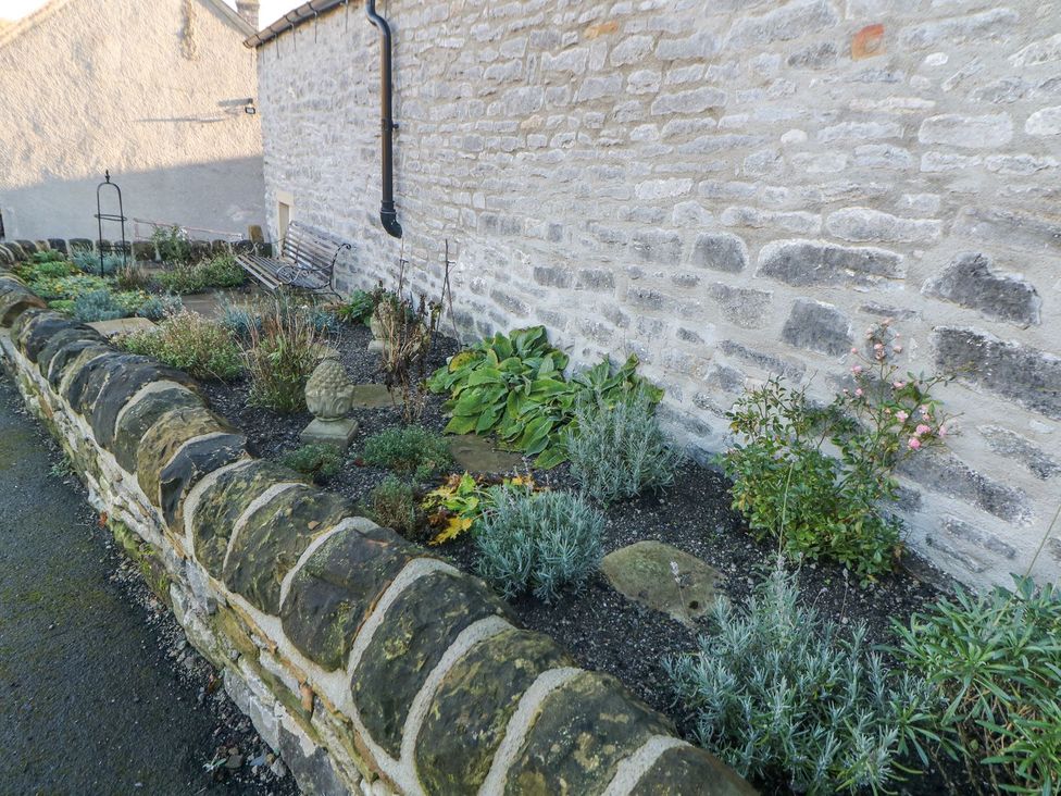 A garden area with a stone wall and plants at Laneside Barn Calver