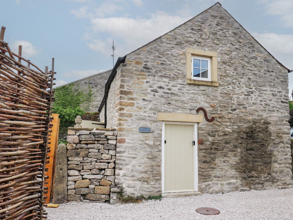 An outdoor area with stone wall and a door at Laneside Barn in Calver