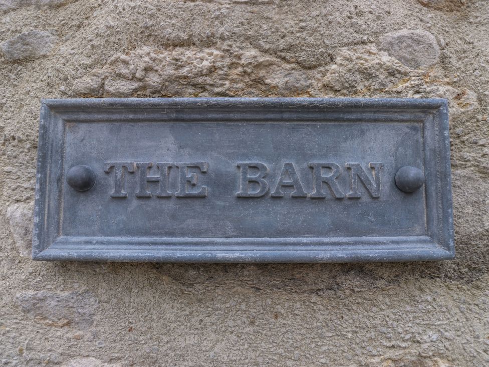 A sign that reads The Barn on a stone wall at Laneside Barn Calver