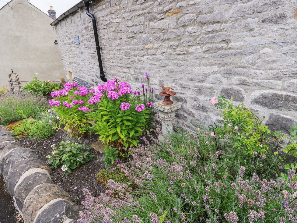 A garden with flowers and a stone wall at Laneside Barn in Calver