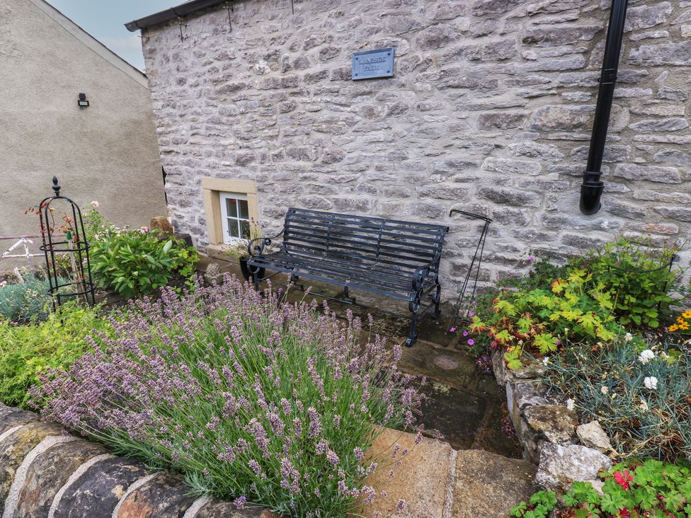 A garden with a stone wall and a bench at Laneside Barn Calver