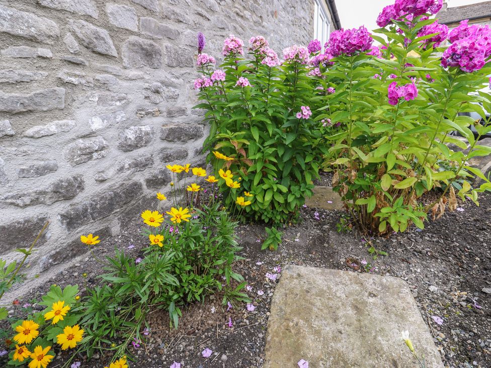 A garden with flowers and a stone wall at Laneside Barn Calver