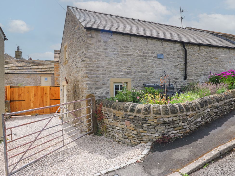 A house with a flower bed and gate at Laneside Barn in Calver