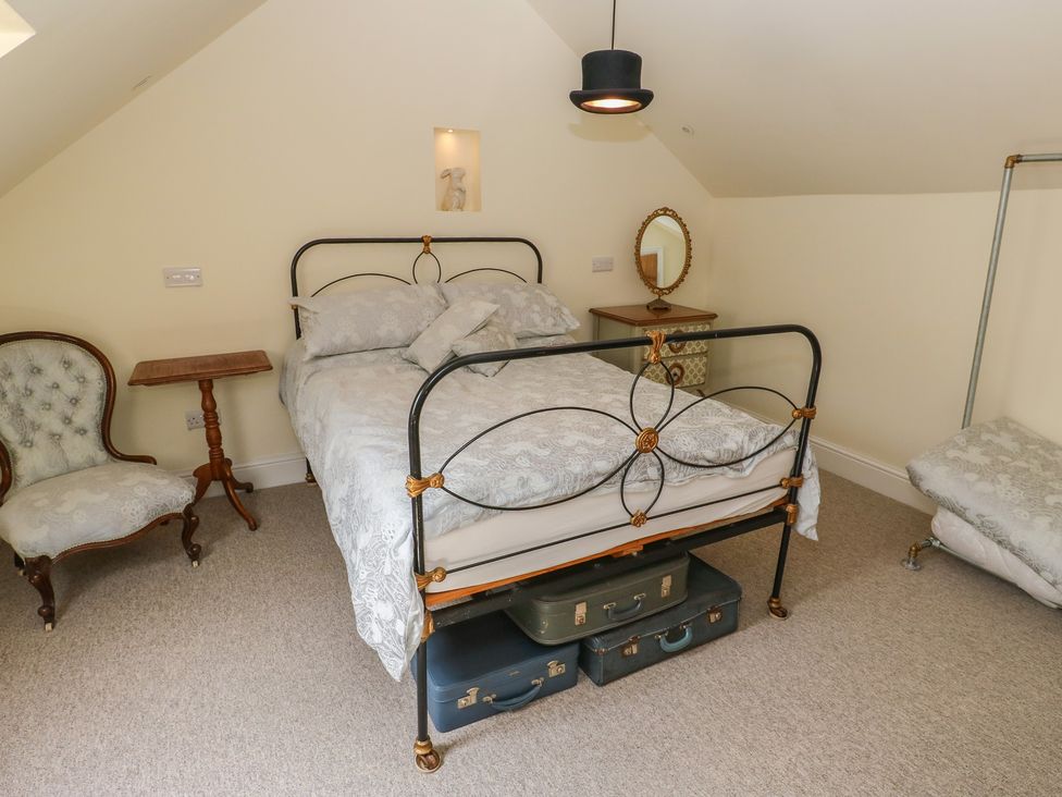 A bedroom with a bed, nightstand, chair, and mirror at Laneside Barn in Calver