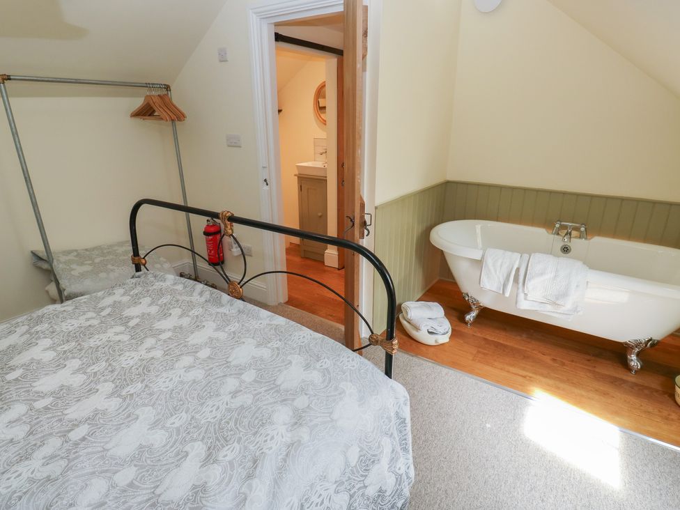 A bedroom with a bed and a bathtub at Laneside Barn Calver