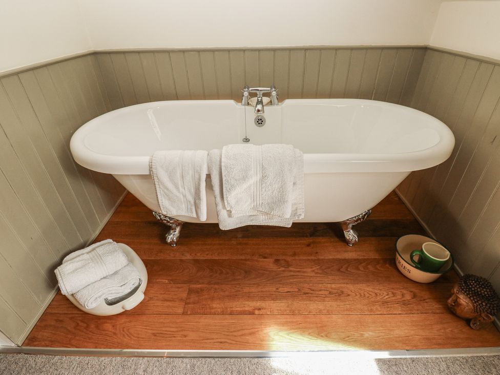 A bathtub with towels and a decorative figure at Laneside Barn in Calver