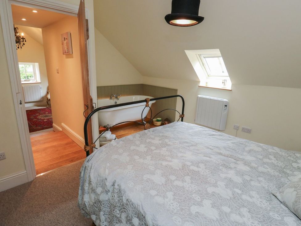 A bedroom with a bed and a bathtub at Laneside Barn in Calver