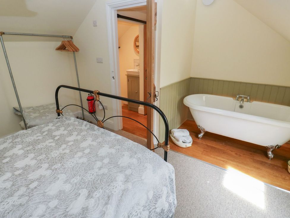 A bedroom with a bed and a bathtub at Laneside Barn Calver