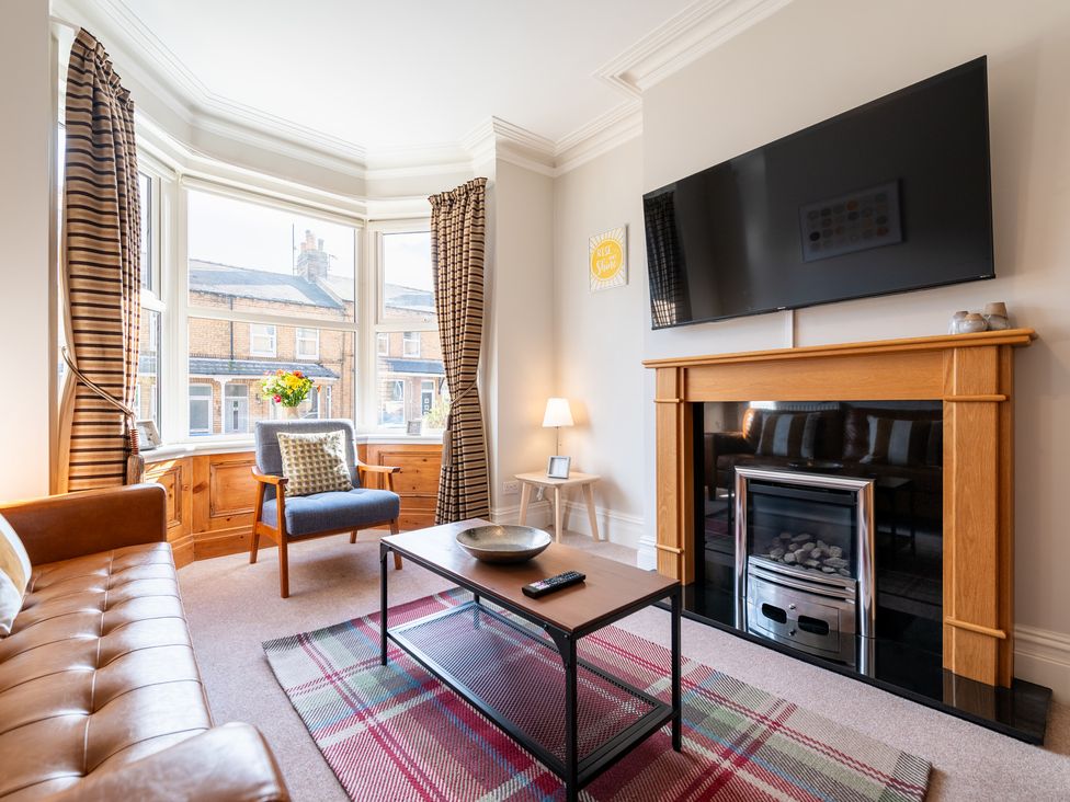 A living room with a sofa, armchair, and television at 18 Mayville Avenue, Scarborough