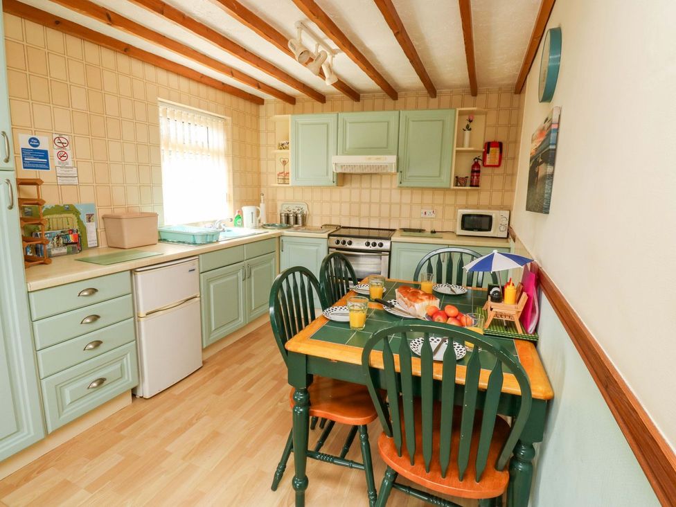 A kitchen with cabinets and a dining table at Cottage 28 in Brixham