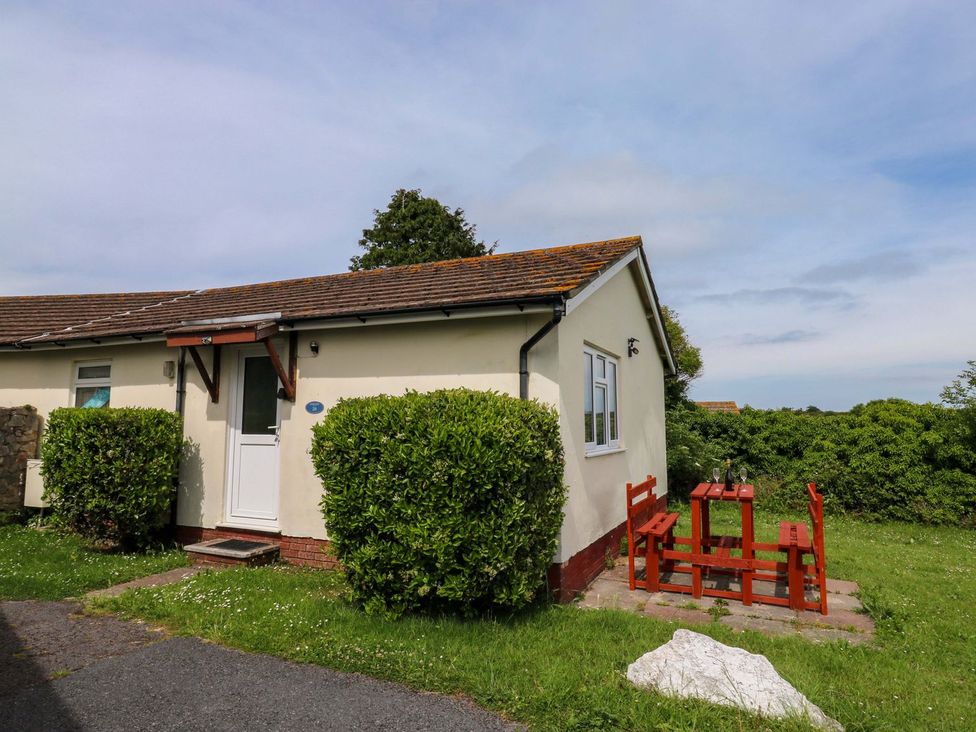 A house with a table and benches outside at Cottage 28 in Brixham