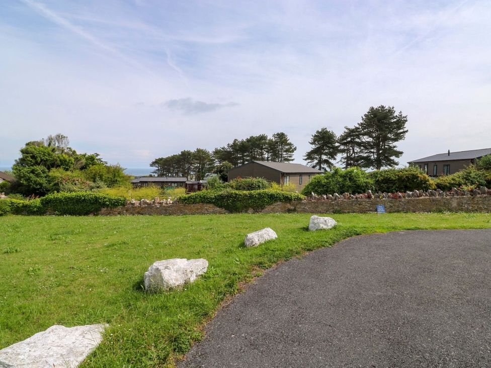 A view of grass, trees, buildings, and a road at Cottage 28 in Brixham