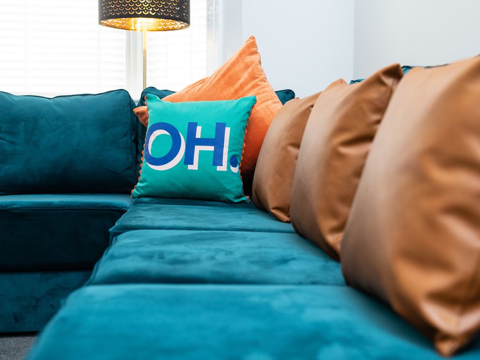 A living room with a teal sofa and cushions at 23 Trafalgar Road in Scarborough