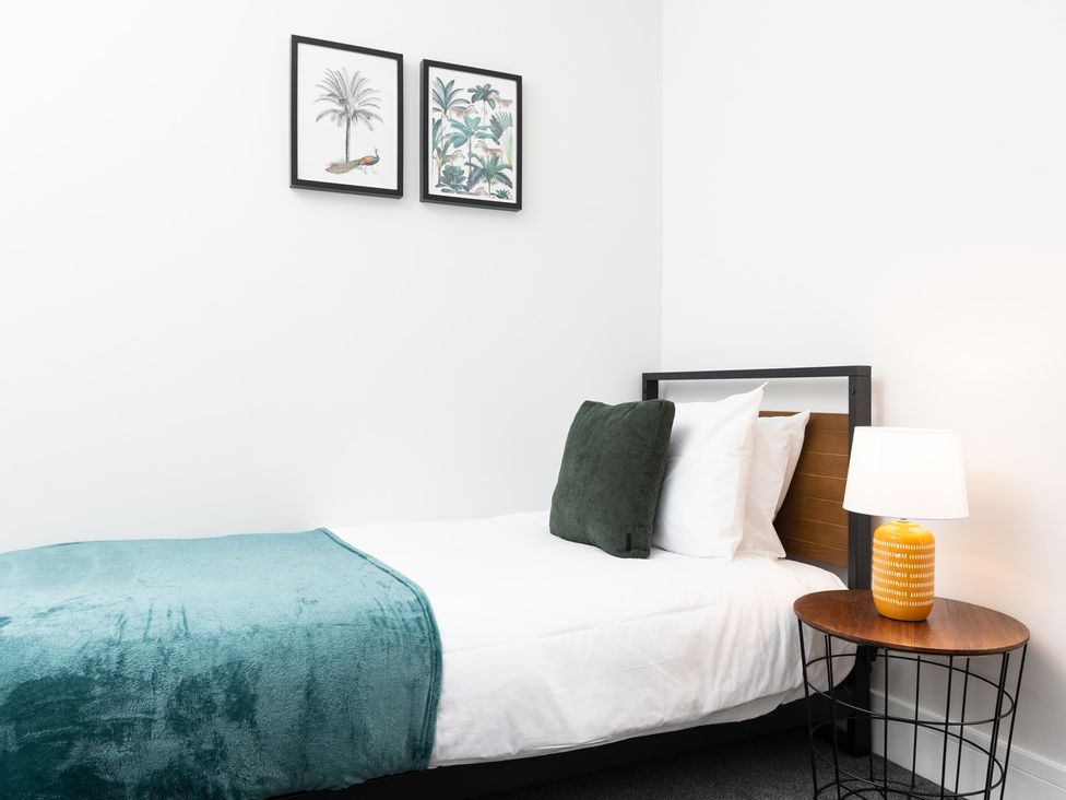 A bedroom with a bed, side table and wall art at 23 Trafalgar Road Scarborough