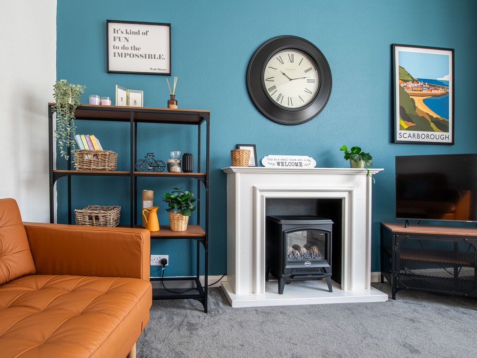 A living room with a sofa, bookshelf, clock, and fireplace at 53A Hampton Road Scarborough