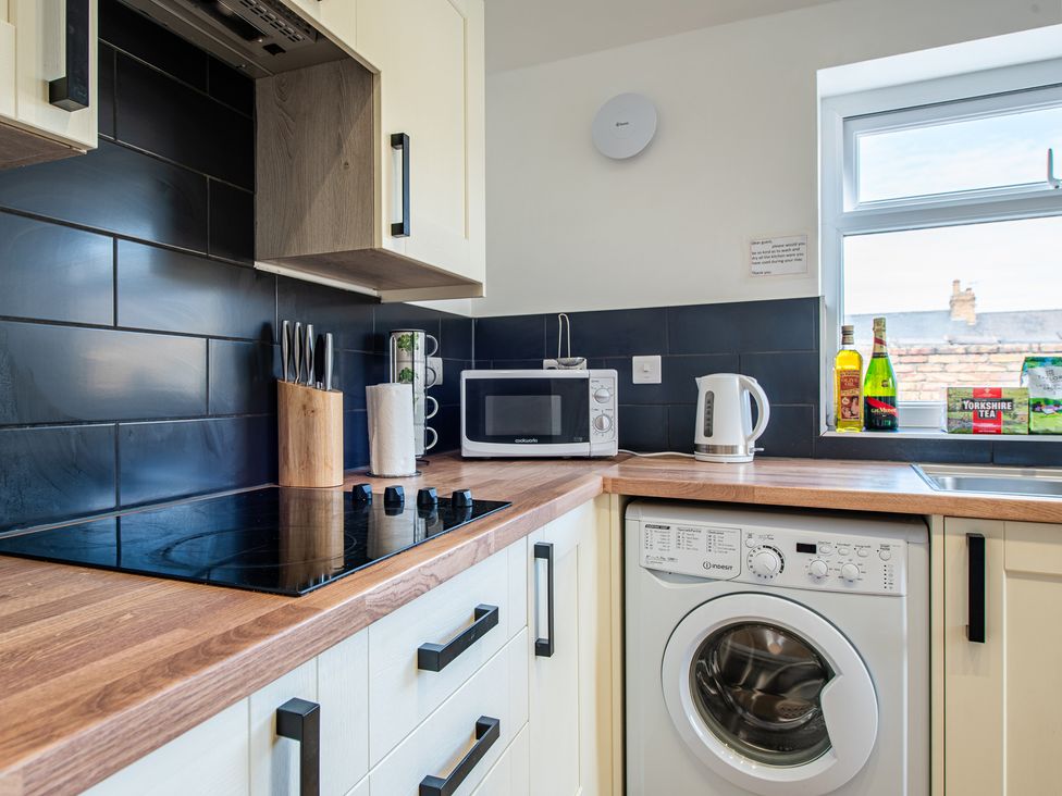 A kitchen with a stove, microwave, kettle, and washing machine at 53A Hampton Road Scarborough