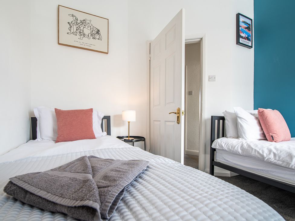 A bedroom with two beds and a bedside lamp at 53A Hampton Road in Scarborough