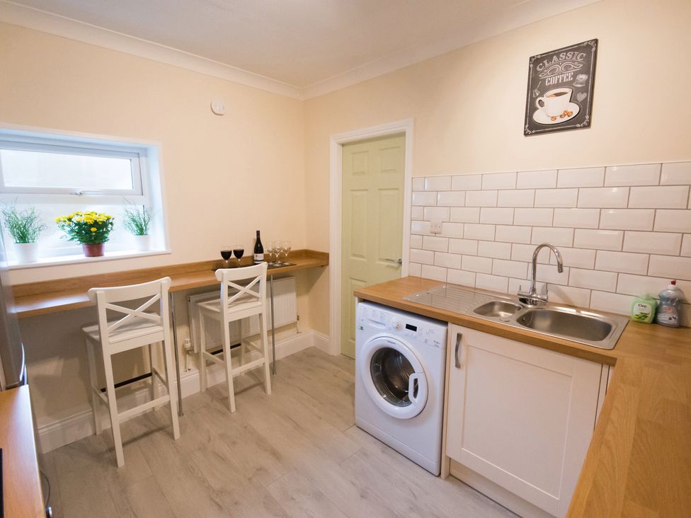 A kitchen with a washing machine and bar stools at 53 Hampton Road in Scarborough