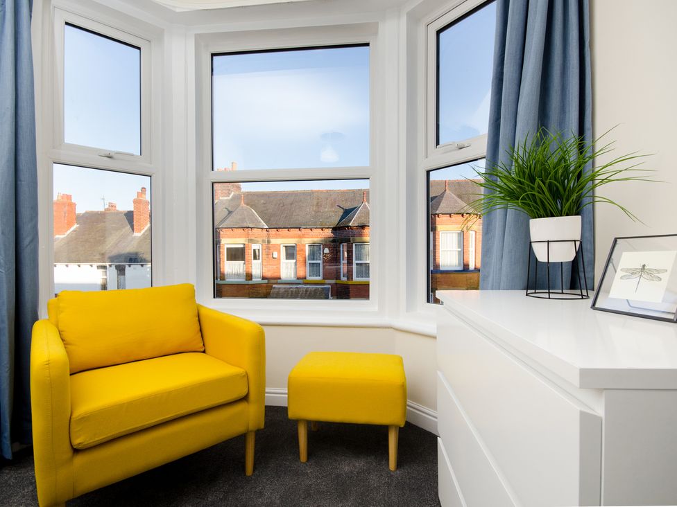 A living room with a yellow chair and ottoman at 46 Ashville Avenue in Scarborough