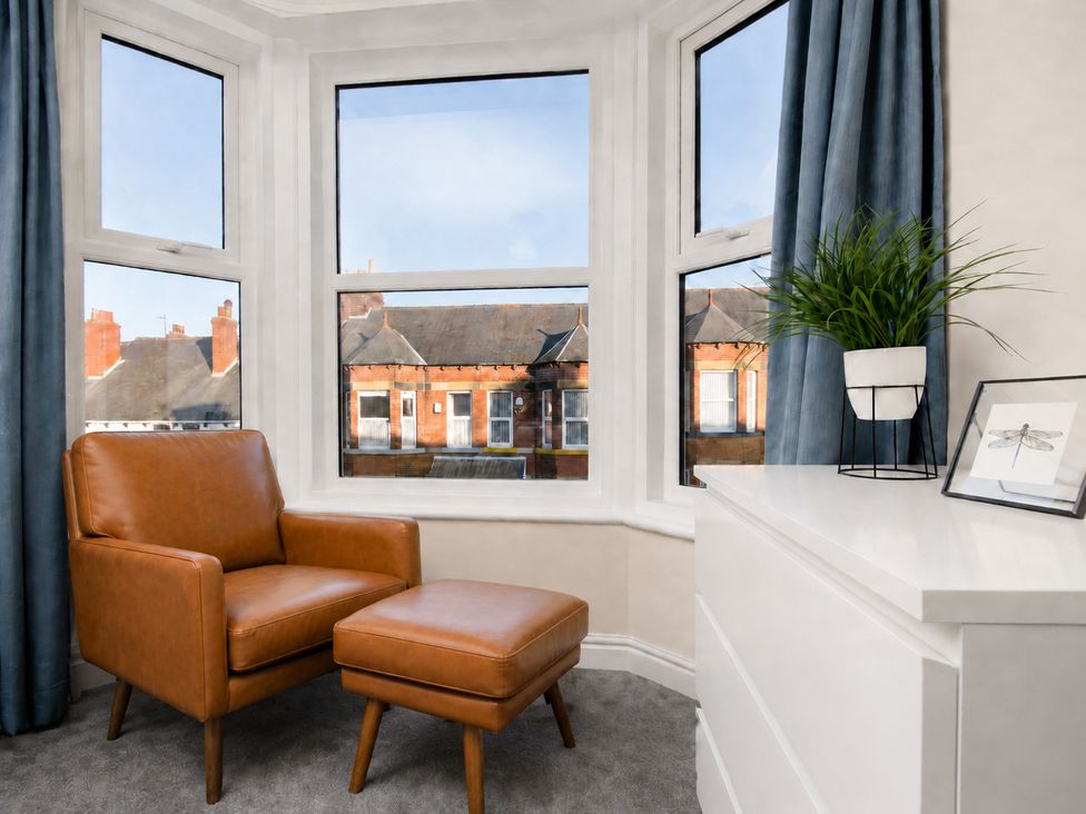 A living room with a chair, ottoman, and plant at 46 Ashville Avenue in Scarborough