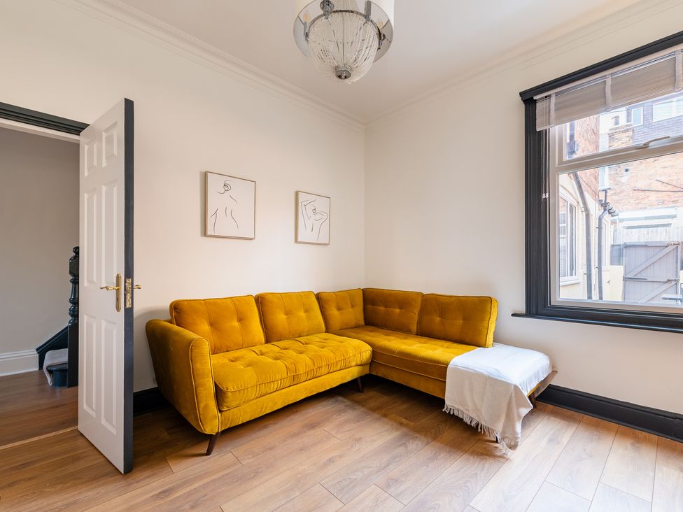 A living room with a yellow sofa and door at 22 Ashville Avenue in Scarborough