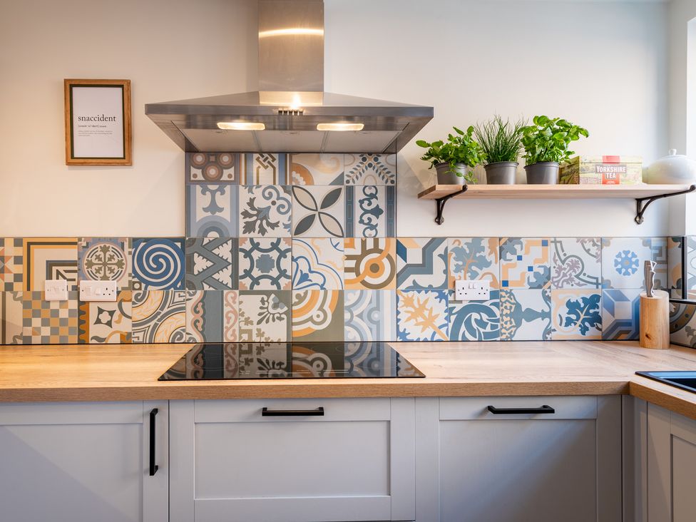 A kitchen with patterned tiles and a shelf holding plants at 22 Ashville Avenue in Scarborough