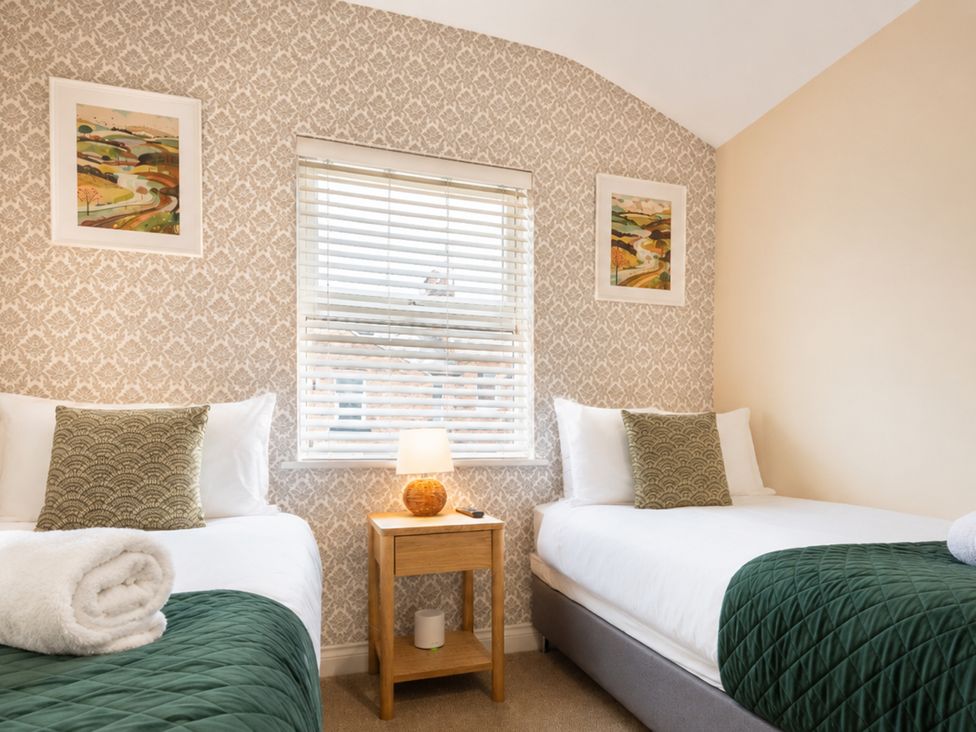 A bedroom with two beds and artwork on the wall at The Ravines in Scarborough