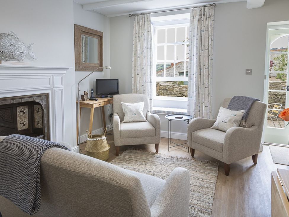 A living room with chairs and a television at Primrose Cottage in Salcombe